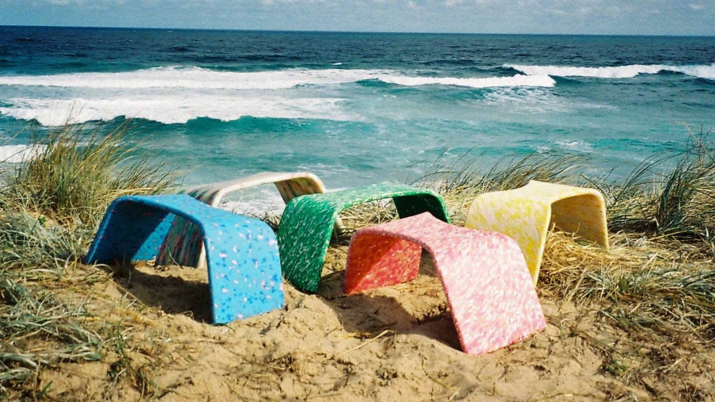 Image depicts recycled plastic poop stools by Hunker sitting on a sandy cliff overlooking the ocean